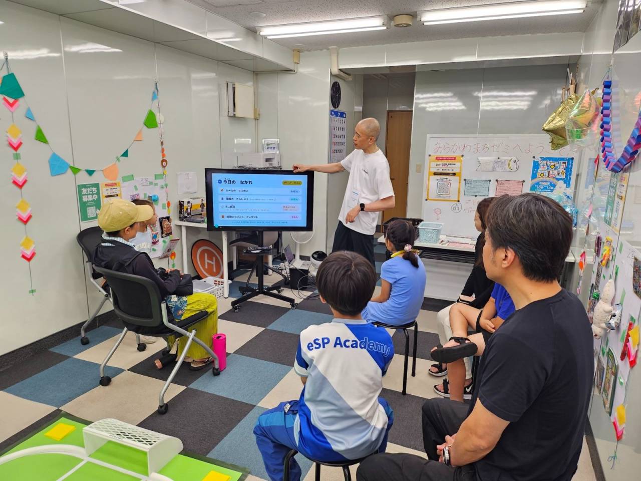 少人数制の子どもドローン教室で、講師がコントローラーの操作方法を教える様子