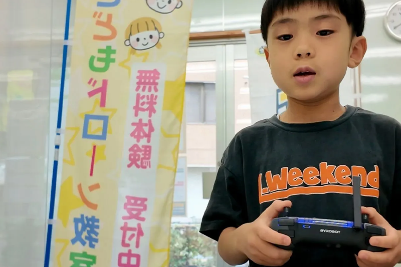 小学生がプロポを操作してドローンを離陸させる様子（東京都荒川区西尾久）