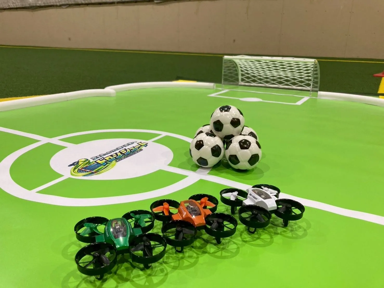 ドローンシュートの公式コートに並ぶ機体とサッカーボール