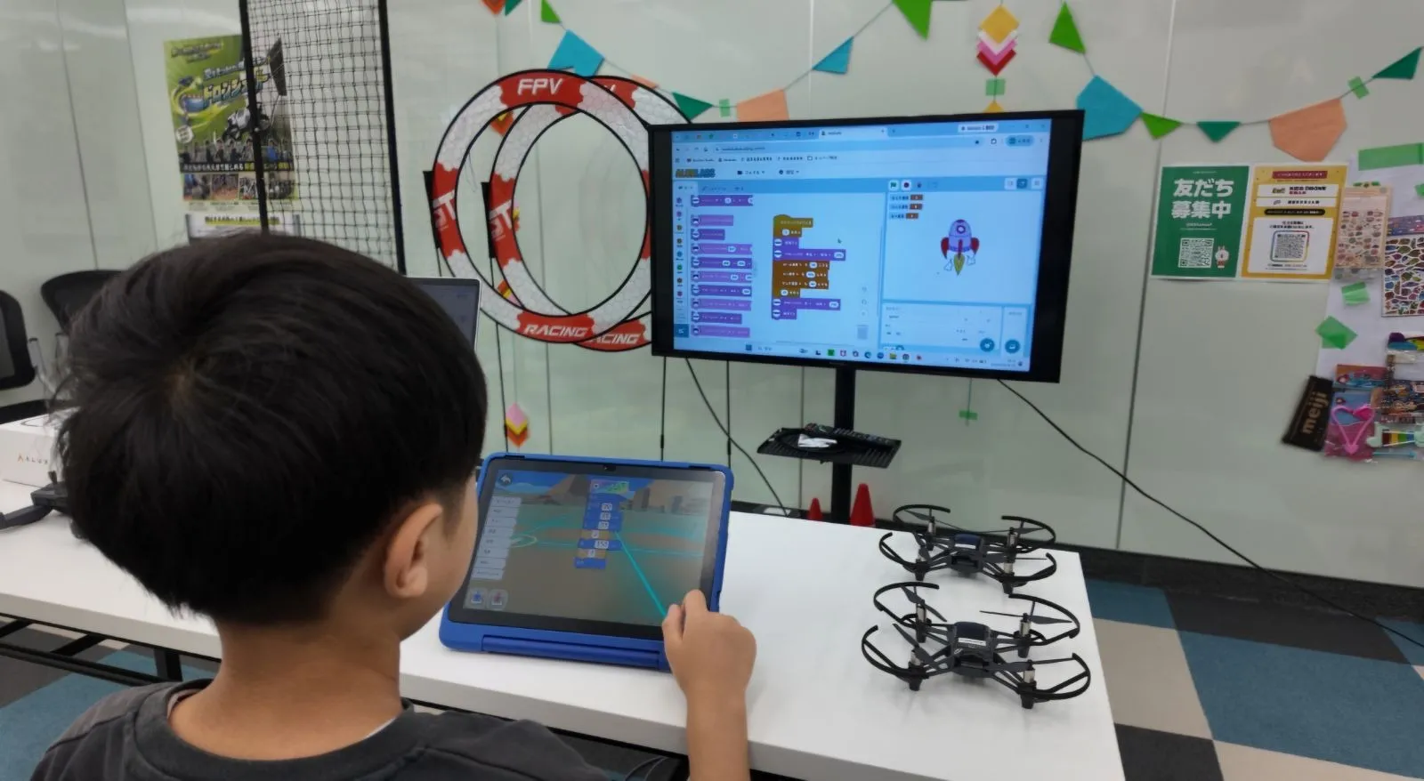 荒川区西尾久のプログラミング教室でタブレットを使いドローンをプログラミングする小学生