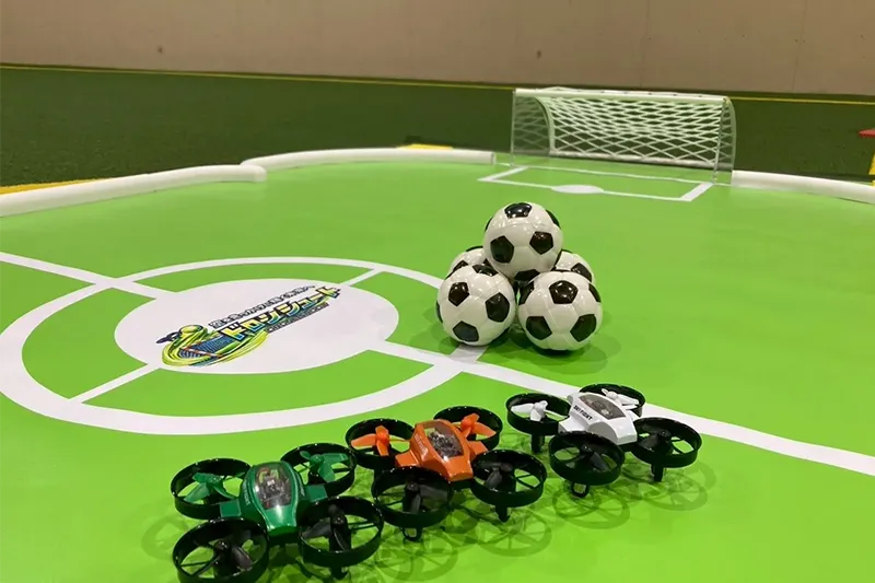 ドローンシュートの公式コートに並ぶ機体とサッカーボール