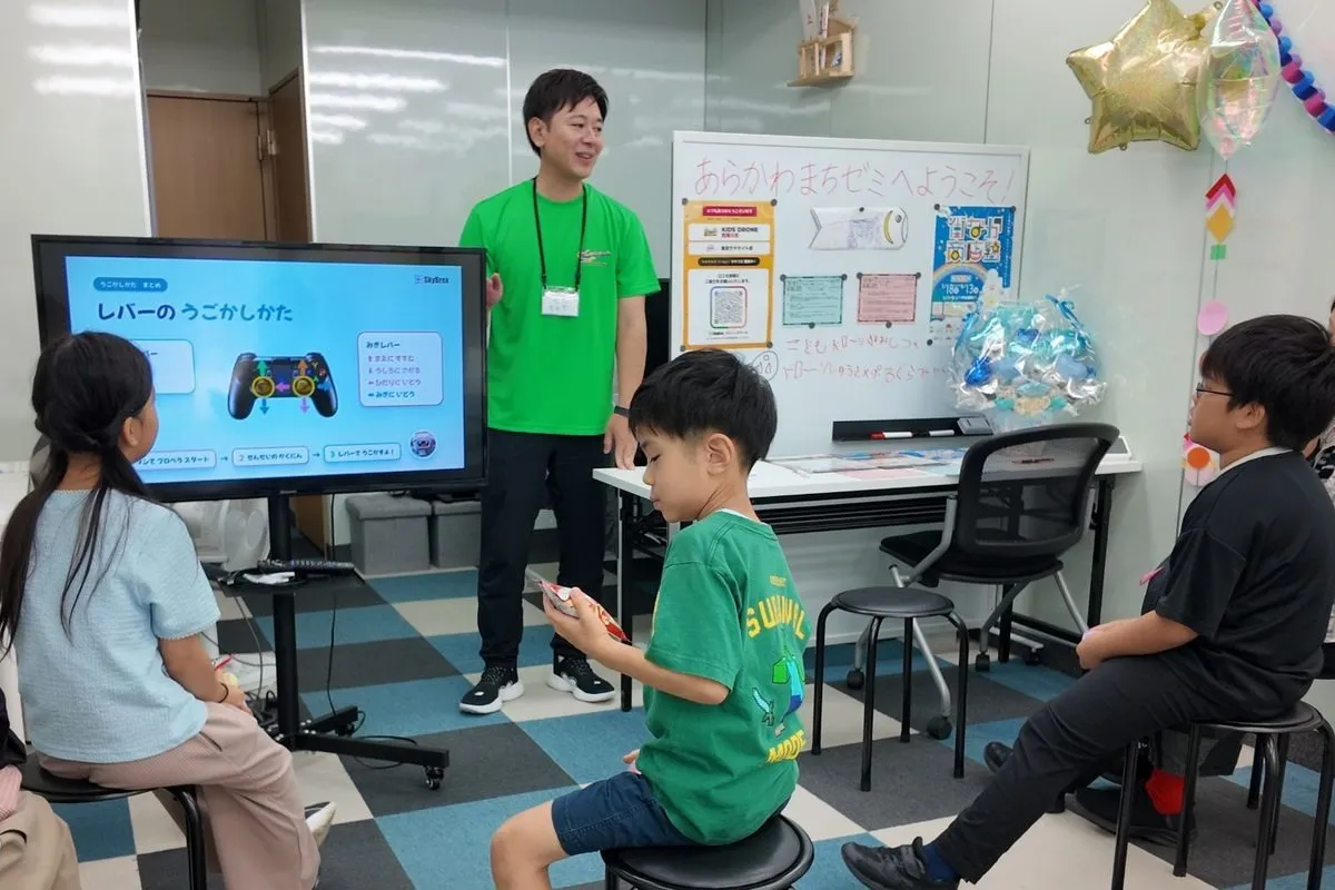 荒川区の子どもドローン教室で、講師が小学生にコントローラーの操作方法と安全のルールを説明している座学の様子